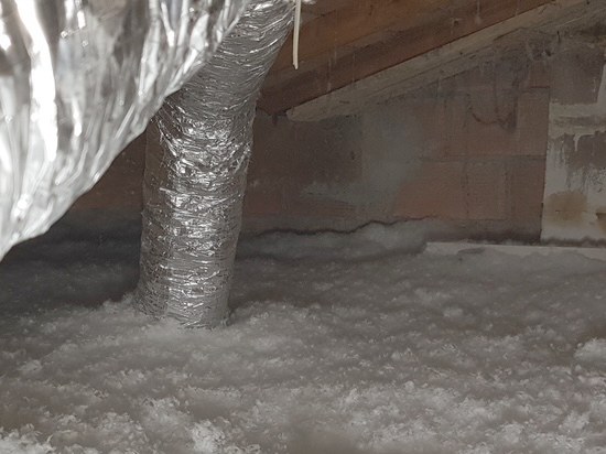 Les mêmes combles une fois isolés : toute la surface de la dalle est recouverte d'une couche de laine soufflée blanche.