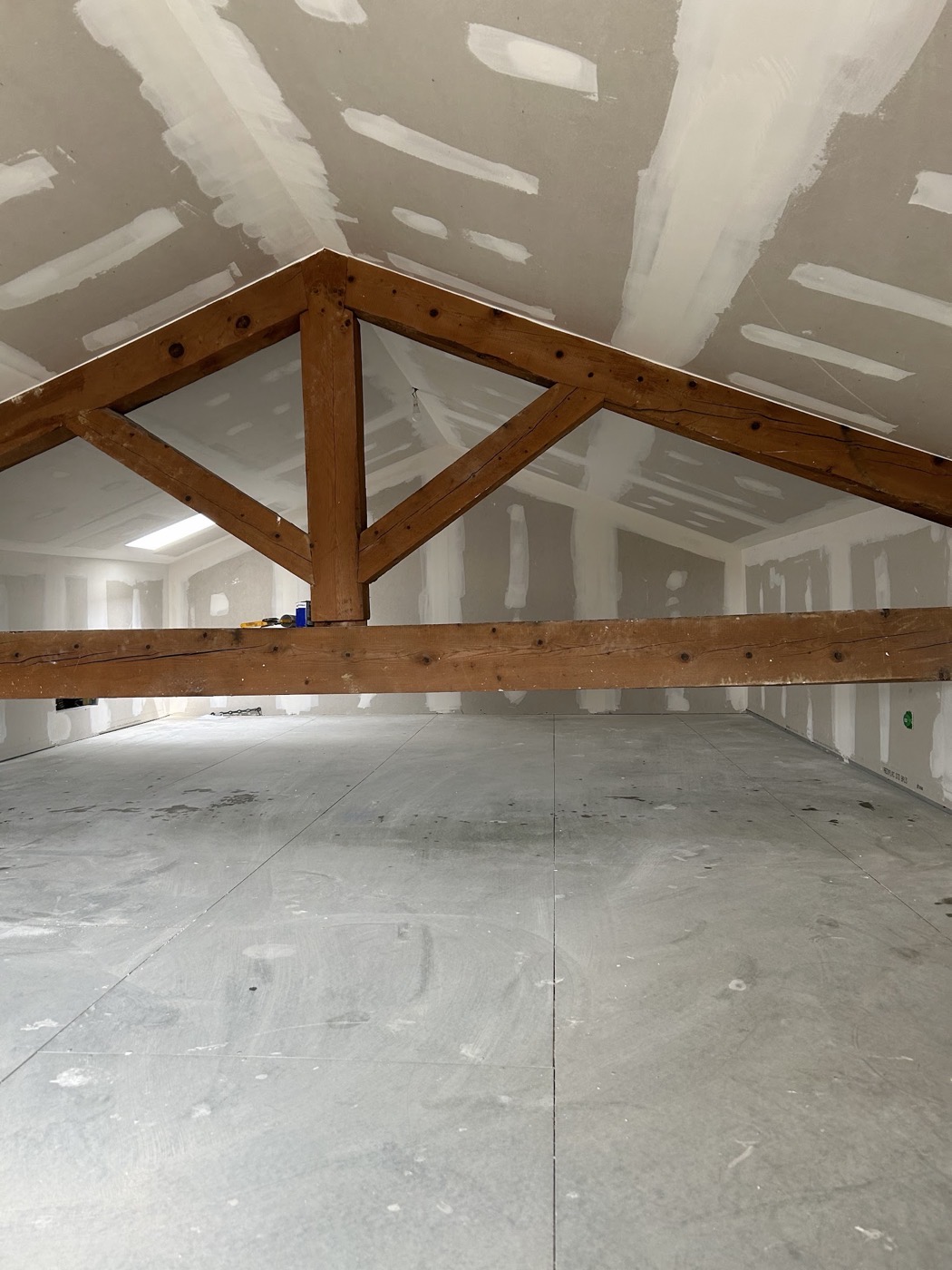 Combles entièrement doublés en plaques de plâtre sous une charpente en bois.