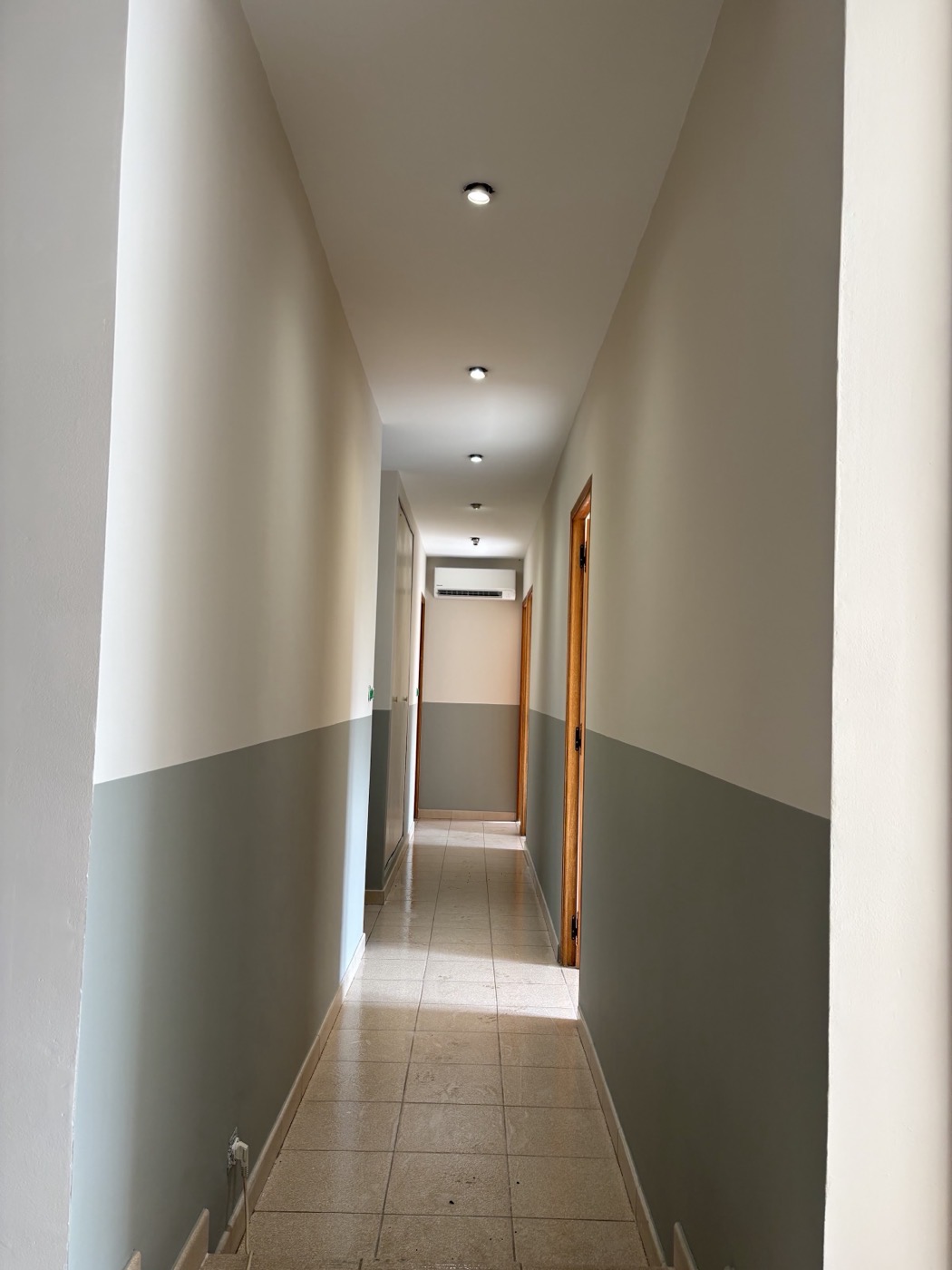 Couloir avec soubassement peint en vert-de-gris et haut de mur blanc.