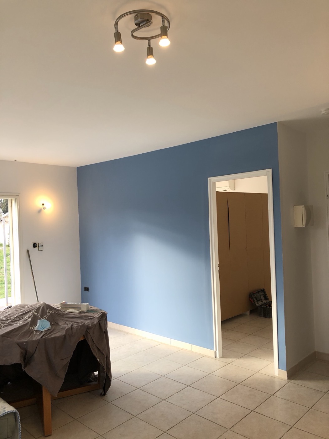 Pan de mur peint en bleu ciel dans une pièce de vie claire.