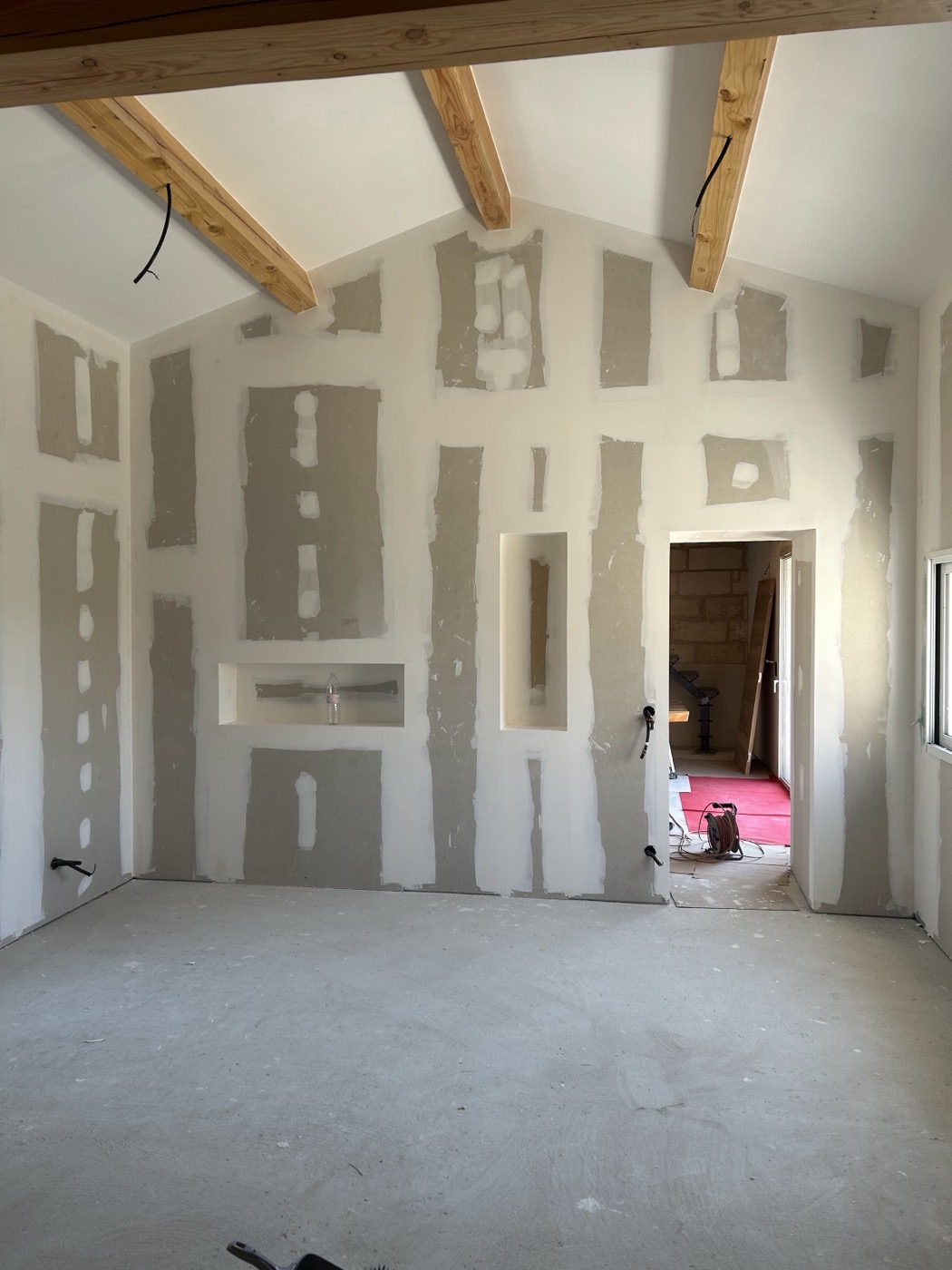 Mur en plaques de plâtre bandé avec deux niches intégrées, sous poutres.