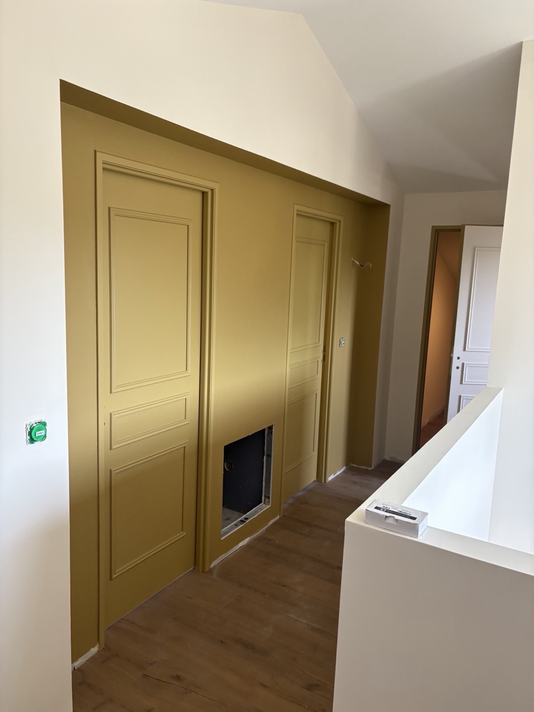 Palier avec mur et portes peints en ocre moutarde, plafond et murs blancs.