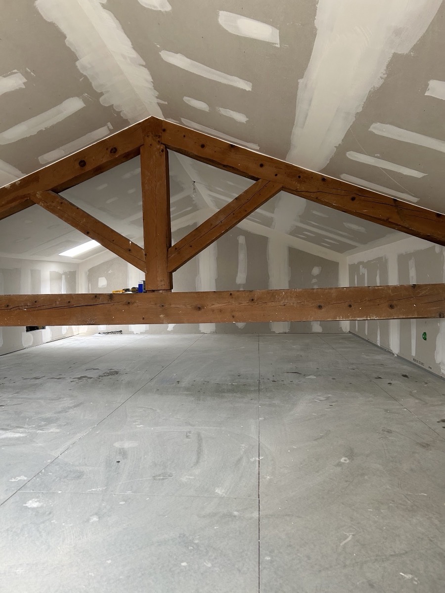 Combles doublés en plaques de plâtre sous charpente en bois apparente.